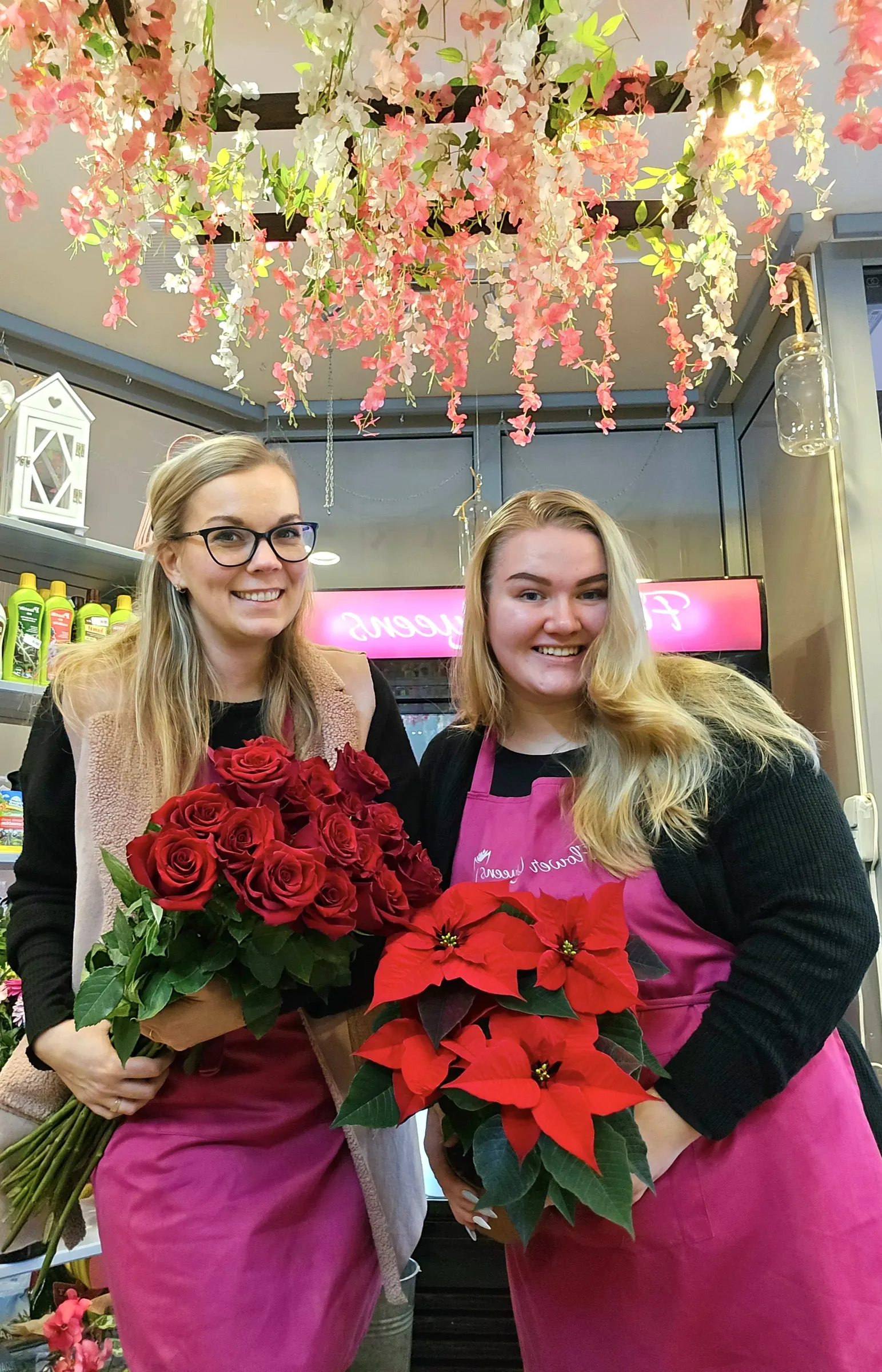 Dvě floristky Flower Queens držící kytice rudých růží v prodejně